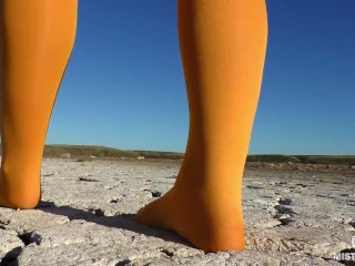 Barefoot walking by dried up lake in yellow pantyhose